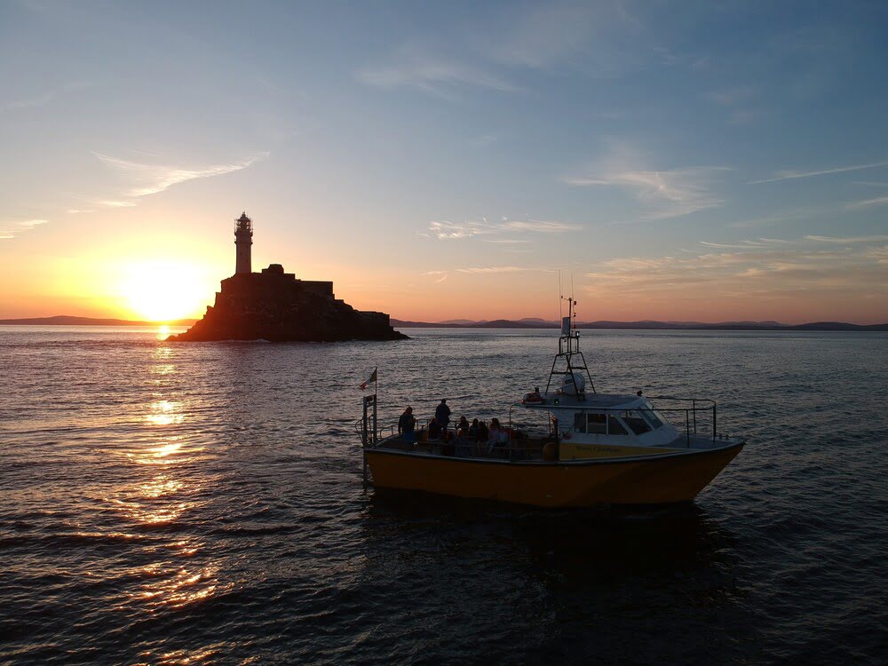 wave chieftain in front of fastnet rock in sunset